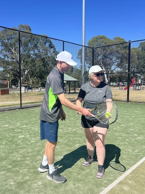 Coach helping a player during a tennis lesson
